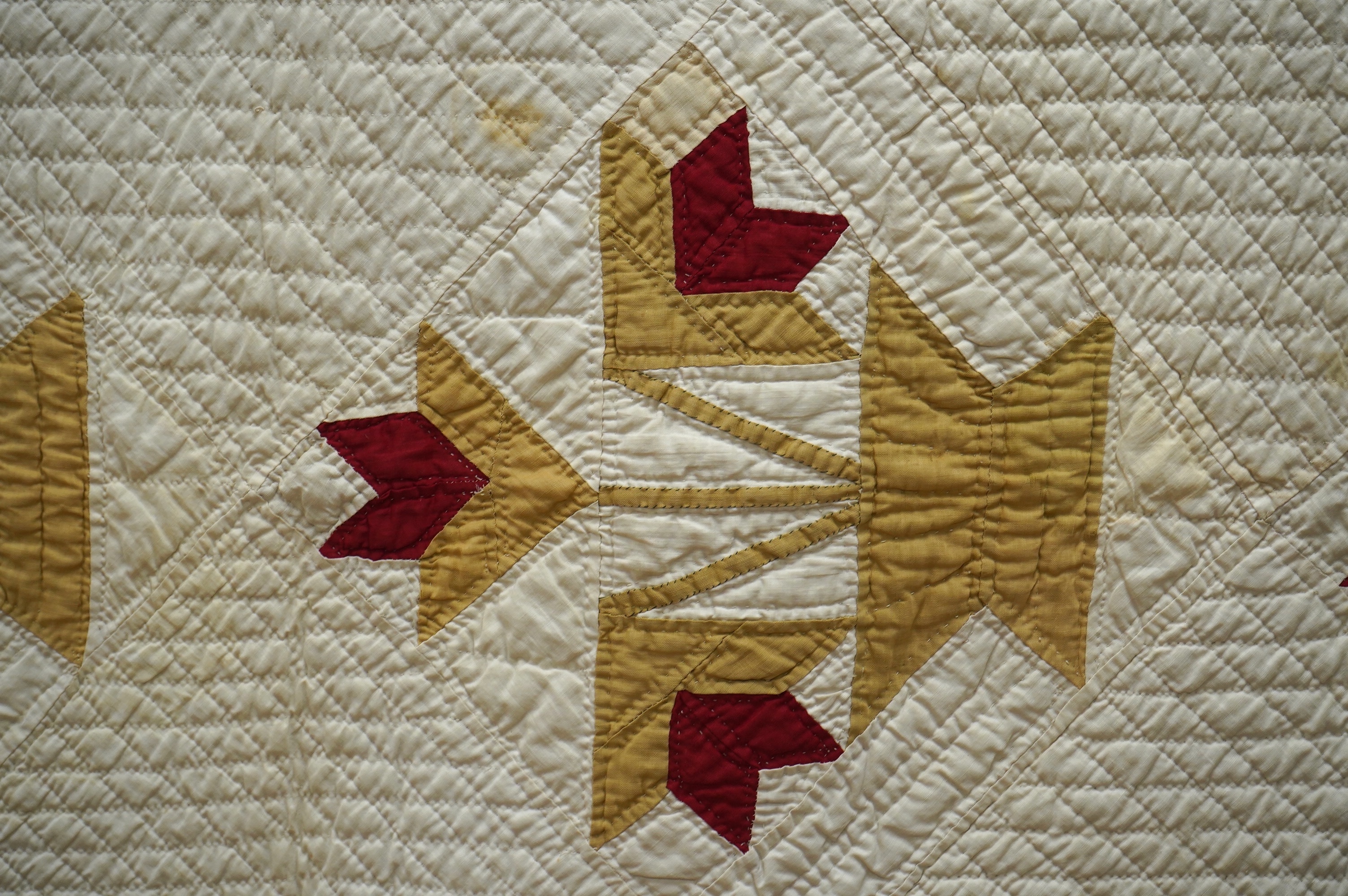 An early 20th century American ‘Carolina Lily’ quilt, worked on a cream cotton in two colours, sand and red patchwork creating motifs of large angular abstracted vases of flowers, the quilt then bordered with red, 185cm